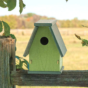 Going Green™ A-Frame Bluebird House on a fence, featuring a hole and a barn-like roof for rain runoff.