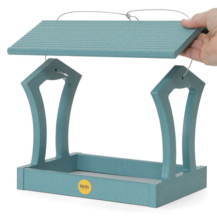 Hand holding Fly-Thru Bird Feeder, Lake Blue with a wide platform, stainless steel fasteners, and a mesh screen for excellent drainage.