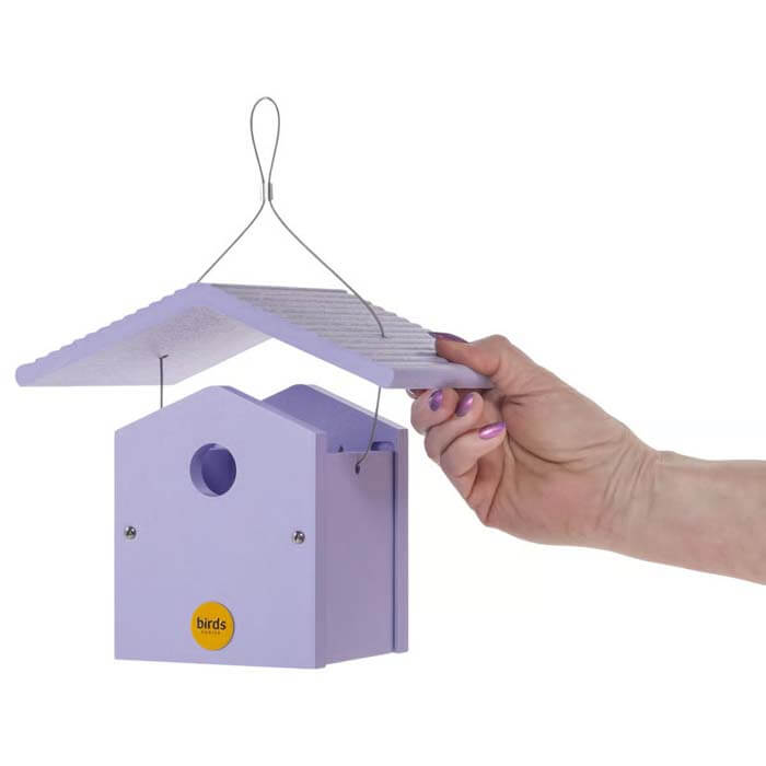 Hand holding a Wren Bird House, Purple, made of durable recycled plastic with a 1-1/4 inch entrance hole and hanging cable.