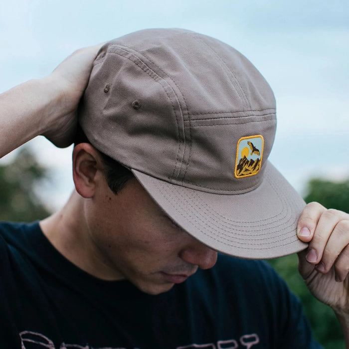 Bird Collective Hawkwatch Camp Hat featuring a Turkey Vulture patch, worn by a man, showcasing the hat's 5-panel design and adjustable strap.