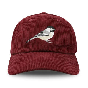 Burgundy corduroy baseball cap with embroidered Black-capped Chickadee, featuring an unstructured 6-panel crown, curved bill, and adjustable fabric strap.