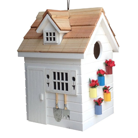 Potting Shed Birdhouse featuring a white structure with a window, tiny potted plants, garden trellis, topiary shutters, and hanging garden tools.