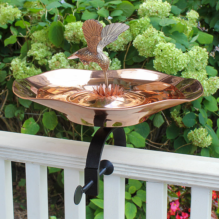 Hummingbird Bird Bath with Over Rail Bracket featuring a detailed brass hummingbird, copper-plated basin, and weather-resistant black wrought iron bracket for easy bird-watching.