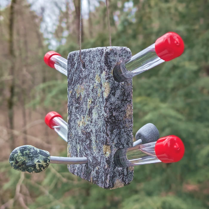 Oasis Hummingbird Glass Tube Feeder with four clear feeding tubes, granite base, and aluminum perches, hanging from a tree.