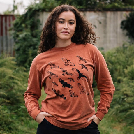 Woman with long curly hair wearing the Bird Collective Hawks In Flight Long Sleeve T-Shirt featuring hawks in flight design.