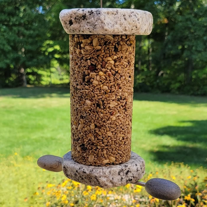 Sea Stones Lifetime Seed Cylinder Bird Feeder made from reclaimed granite, featuring rocks inside, designed for easy refilling and durability in outdoor garden spaces.