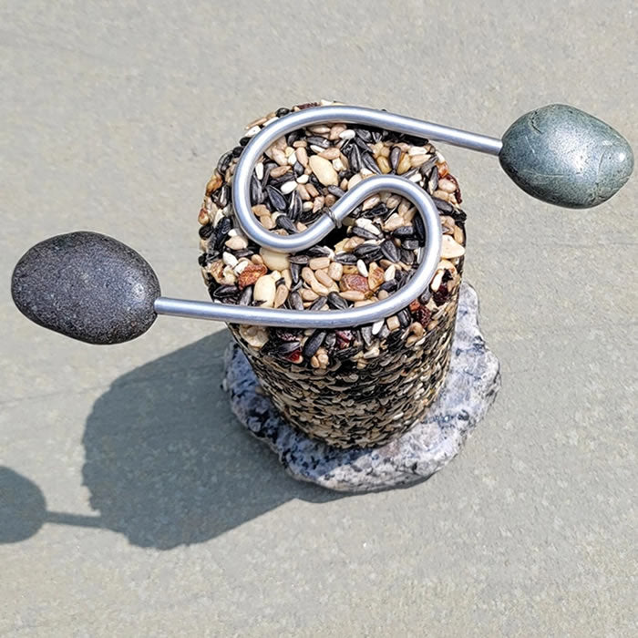 Sea Stones Featherweight Granite Cylinder Feeder on a rock, showcasing its handcrafted, eco-friendly design. Holds 4x8 inch seed cylinders.