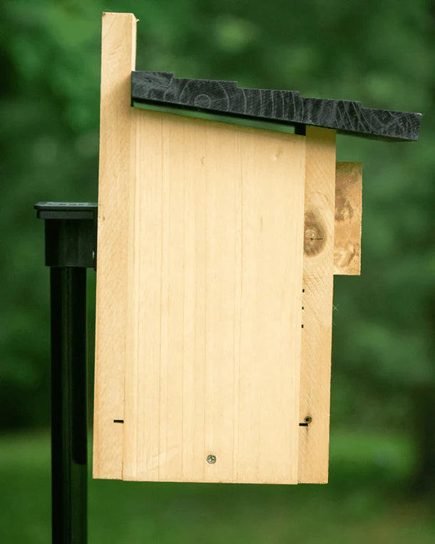 Brome BirdsUP Mounting Flange displayed on a wooden birdhouse with a black roof, illustrating its use for attaching accessories to a 1-inch pole.