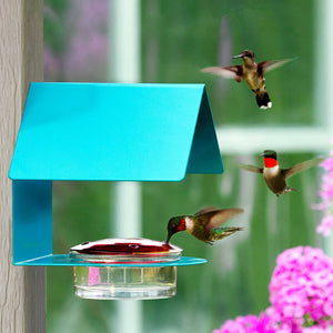 The Cottage Hummingbird Feeder Aqua features a glass dish with four feeding ports, nestled in a sturdy steel frame, attracting hummingbirds to rest and feed.