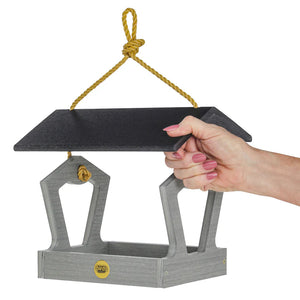 Hand holding the Modern Farmhouse Fly-Thru Bird Feeder, showcasing its open platform design and durability, crafted from recycled driftwood plastic with mesh drainage and stainless steel fasteners.