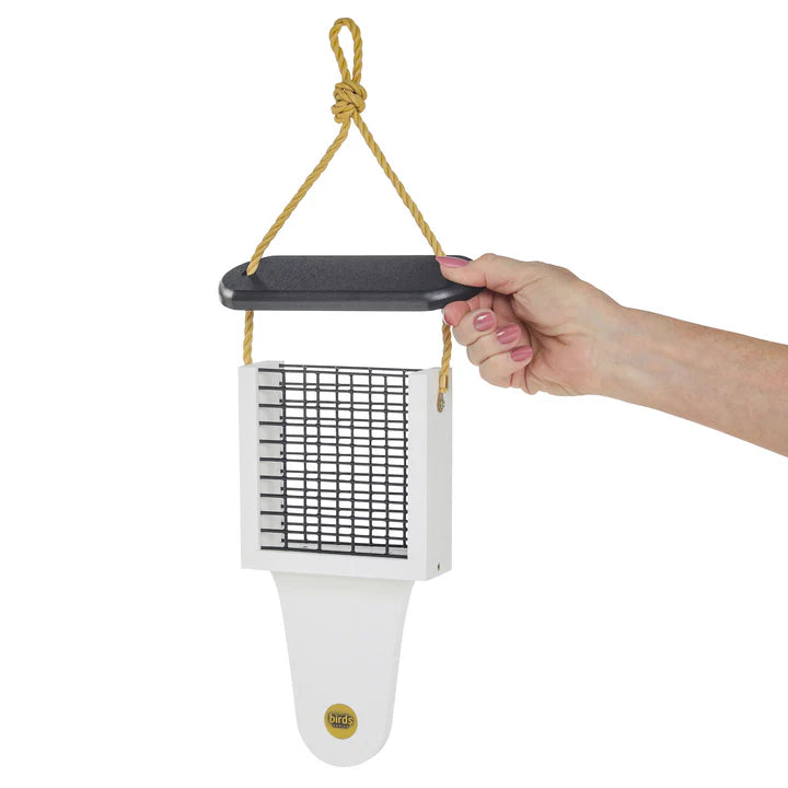 Hand holding the Modern Farmhouse Suet Feeder with Tail Prop, featuring a white square design and yellow rope, perfect for attracting woodpeckers.