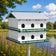 Purple Martin House  on a pole with a natural background of trees and flowers