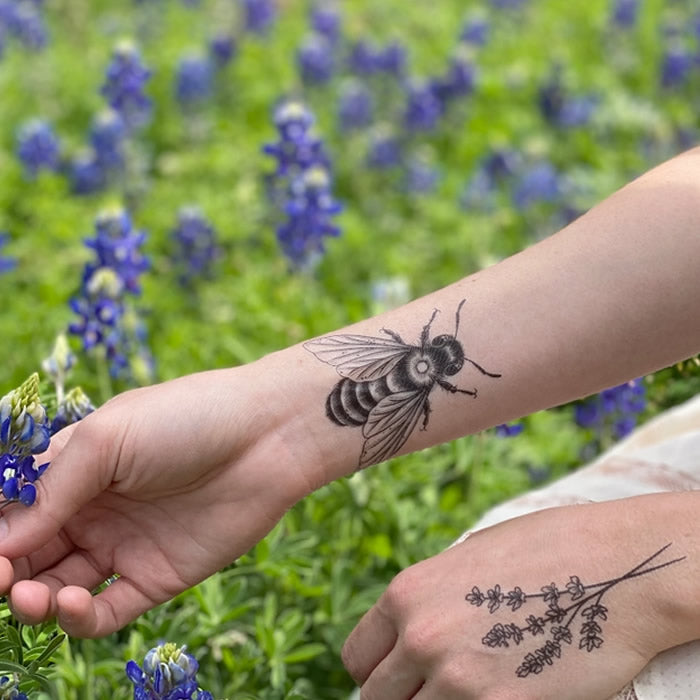 Big Bee Temporary Tattoo on a person's arm outdoors, featuring a detailed bee design amidst lavender and grass, showcasing a nature-inspired art piece.