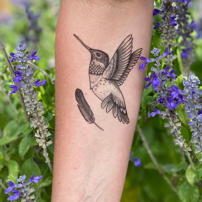 Hummingbird Temporary Tattoo featuring a detailed design of a hummingbird and an additional feather, capturing nature's essence with bold black lines.