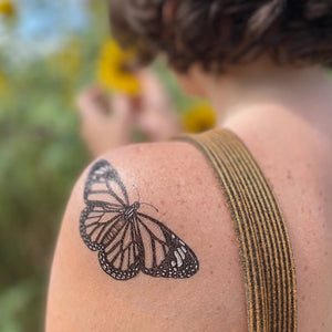 Monarch Butterfly Temporary Tattoo on a woman's shoulder, showcasing a detailed, hand-drawn design with bold black lines, highlighting its elegance and precision.