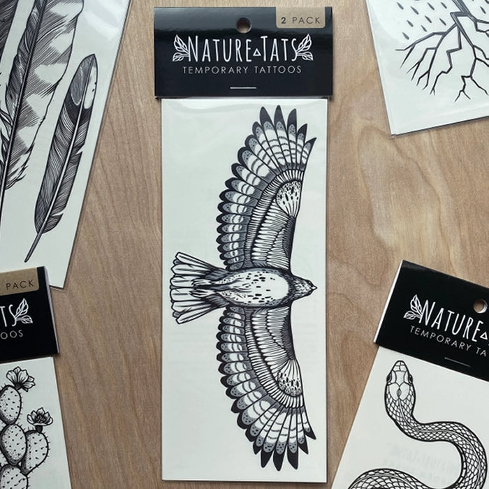 Hawk Temporary Tattoo featuring a hand-drawn Red-Tailed Hawk with a 6.5-inch wingspan, displayed among nature-inspired stickers on a table.