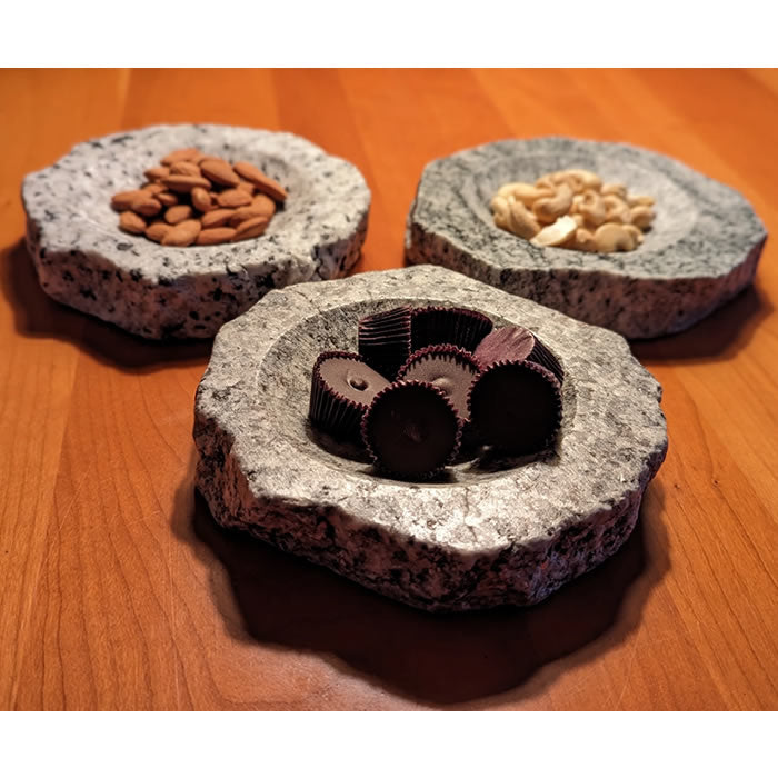 Reclaimed Granite Dish Nest with almonds, cashews, and chocolates in stone bowls showcasing its rustic and eco-friendly design for bird feeding.