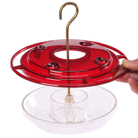 Hand holding the 8 oz. Hummerfest Hummingbird Feeder with clear basin, four feeding stations, and a red cover.