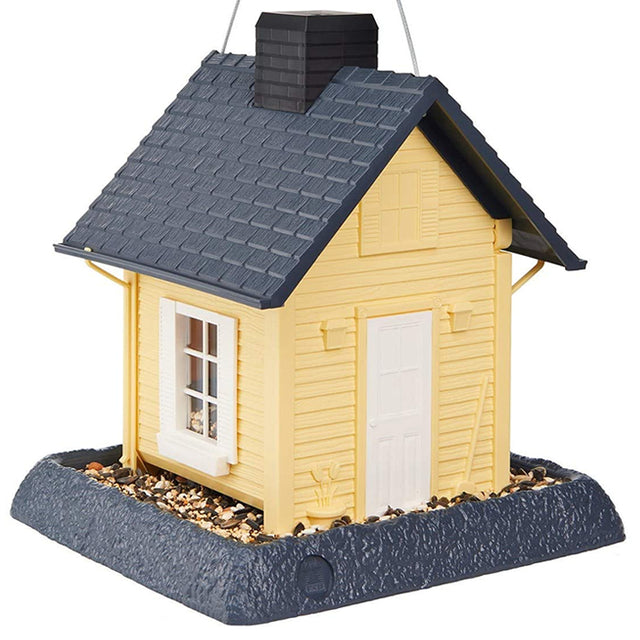 Yellow Cottage Bird Feeder, featuring a black roof, white-framed windows, and a removable chimney for easy refilling. Durable plastic with a wire hanger for backyard use.