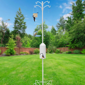 Bird feeder pole with multiple bird feeders on a grassy lawn with trees in the background
