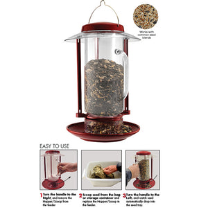 Combination Hopper & Seed Scoop Feeder with removable glass container, shown filled with seeds. A hand holding a bag of seeds nearby.