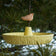 Platter Bird Feeder hanging from a tree, features a rough edge for perching. Handcrafted stoneware with brass chain, perfect for outdoor bird feeding.