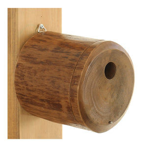 Pivot Bird Home: Wooden cylinder-shaped birdhouse with a 1-1/8 inch entry hole, front panel for cleaning, and mounting tab for flat surfaces.