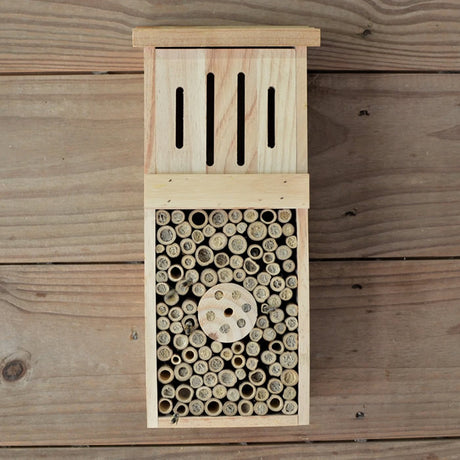 Pollinator Tower: Rectangular wooden insect house with multiple holes, featuring hollow bamboo tubes and pre-drilled wood blocks for attracting and sheltering pollinating insects and birds.