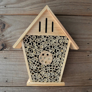 Insect Chateau: A wooden insect house featuring hollow bamboo tubes and pre-drilled wood blocks with various hole sizes for attracting beneficial pollinators and birds.