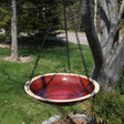 Hanging Radial Bird Bath, Autumn Red, with a chain, mounted on a tree, featuring a glazed stoneware basin for birds to drink and bathe.