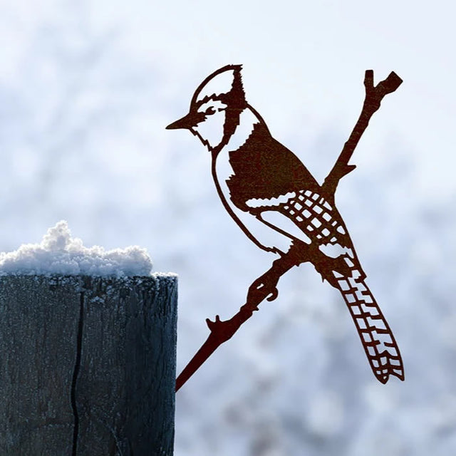 Metal Blue Jay perched on a snowy branch, crafted from durable Corten Steel, designed to age beautifully, adding a unique charm to any garden.