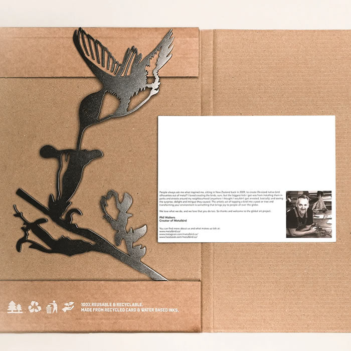 Metal Hummingbird sculpture in a cardboard box with a white card, showcasing a precision-cut bird design made from durable Corten Steel.