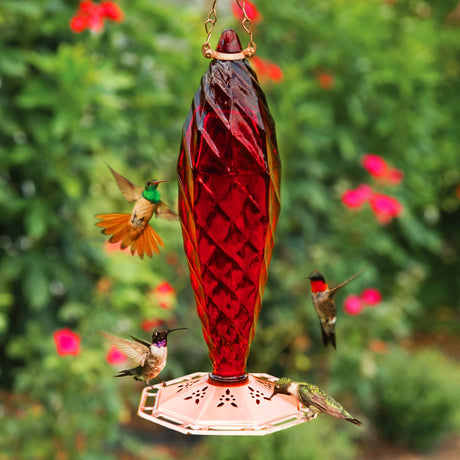 Crystal Spiral Glass Hummingbird Feeder with red reservoir, attracting hummingbirds, featuring eight feeding ports, decorative copper top, and an 18 oz. capacity.