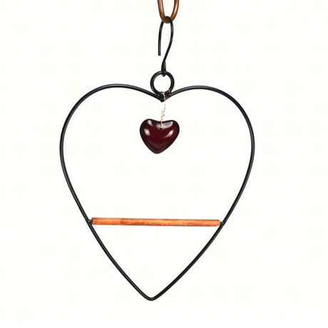 Tweet Heart Birdie Swing Black: A heart-shaped metal swing with a wooden perch, featuring a red bead, designed for hummingbirds to rest and preen.