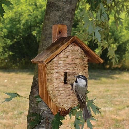 Mounted Grass Roosting Pocket with Roof: A bird perches on a wooden birdhouse, showcasing a natural reed grass pocket with a cedar roof, perfect for sheltering small birds.