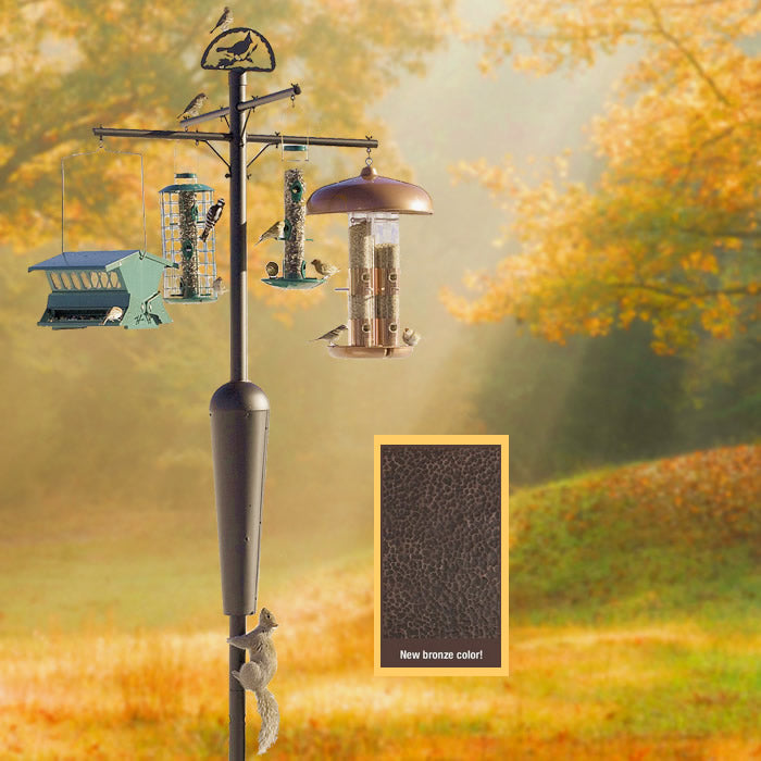 Squirrel Stopper System, Bronze (SOLD OUT) bird feeder on a pole in a grassy outdoor setting with trees in the background.