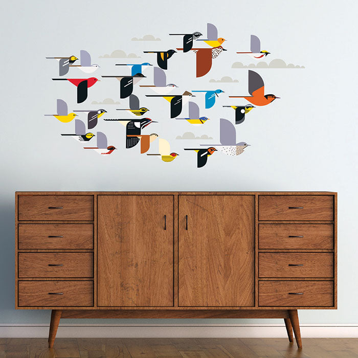 Charley Harper A Flock of Birds Wall Décor featuring a wooden cabinet adorned with bird stickers and additional decorative elements like clouds and stars.