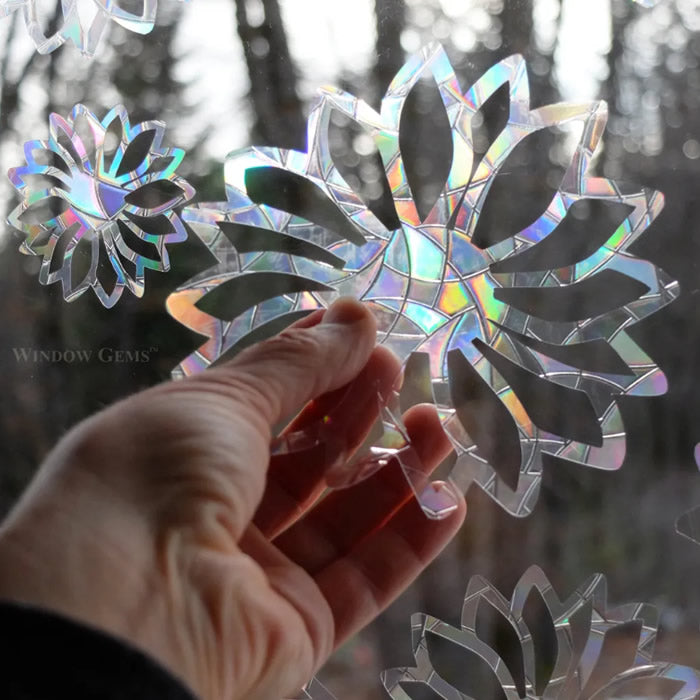 Hand holding a Flower Window Gem, part of a set of 9 prismatic decals designed to prevent bird strikes and beautify windows.