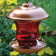 16 oz. Ruby Glass Hummingbird Feeder with red metal flower ports, featuring a red glass reservoir and coppertop, shown with a hummingbird feeding.
