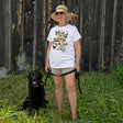 Butterflies of North America T-Shirt: Woman with sun hat standing beside a black dog in grass, holding a strap.